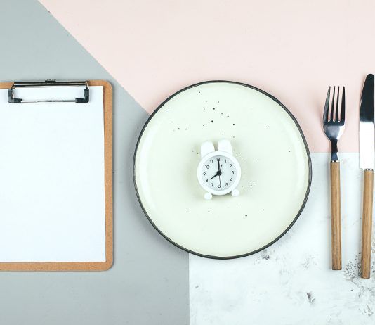 plato vacío, reloj y libreta representando el ayuno